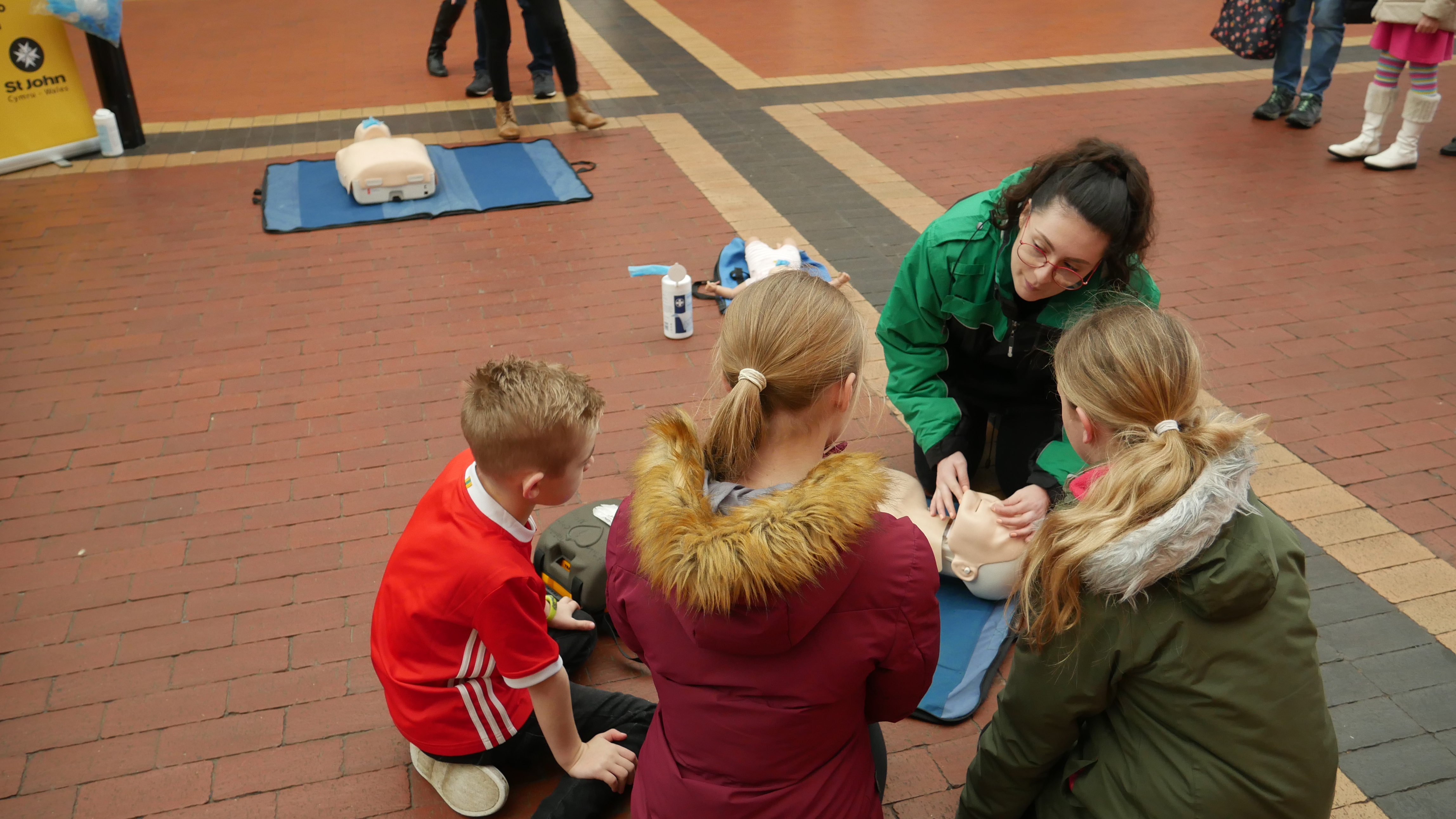 A woman shows three children how to use a defibrillator